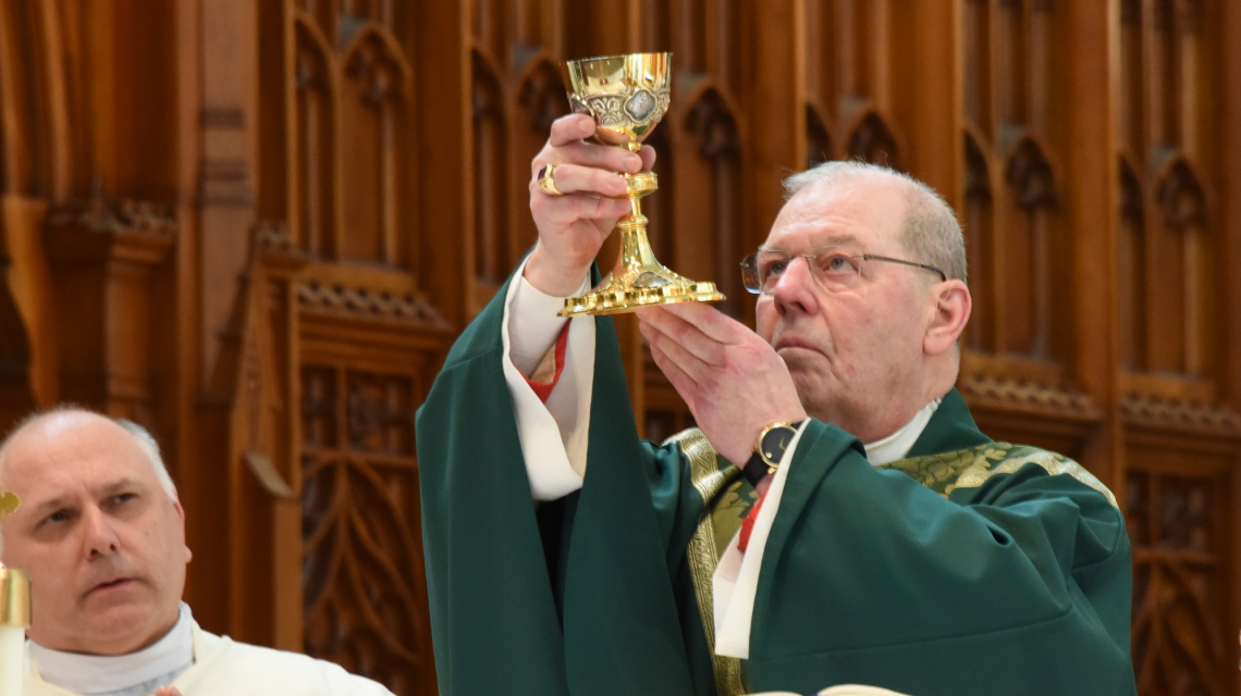 Bishop Robert Deeley holding up a chalice at the Basilica of Ss. Peter & Paul in Lewiston.