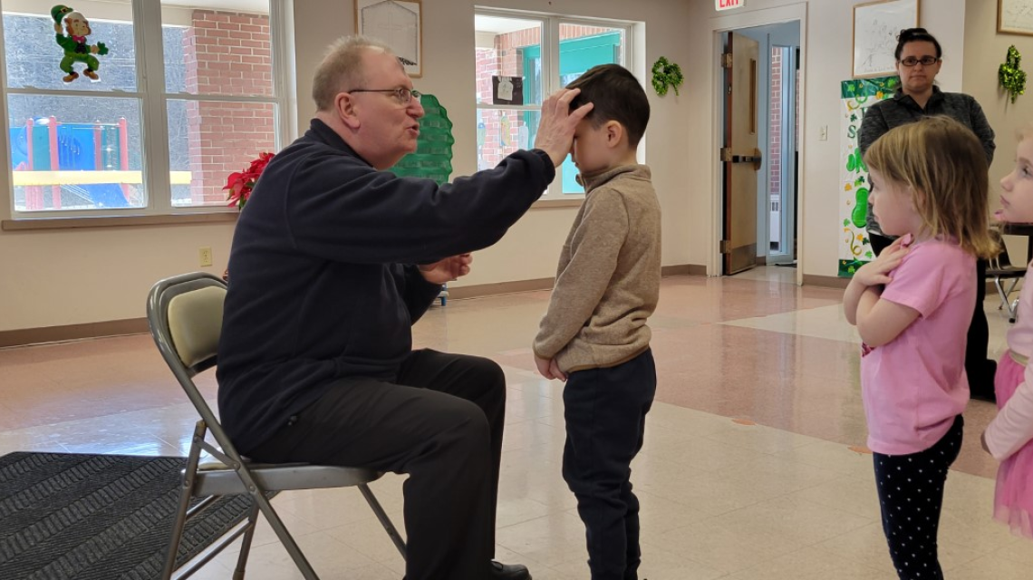 Monsignor Dubois distributes ashes to children at All Saints Catholic School in Bangor. 