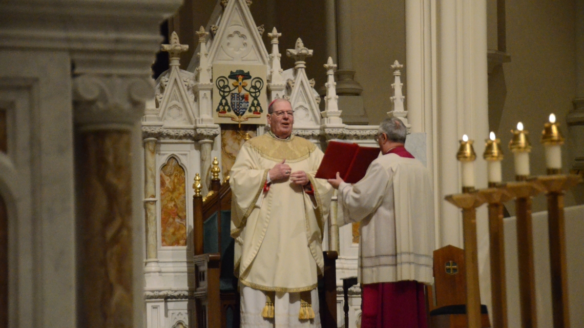 The bishop reads from a book from the altar