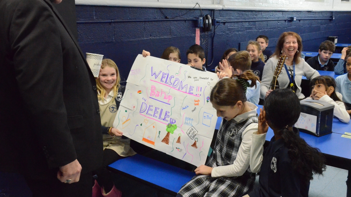 two students hold up a sign for the bishop