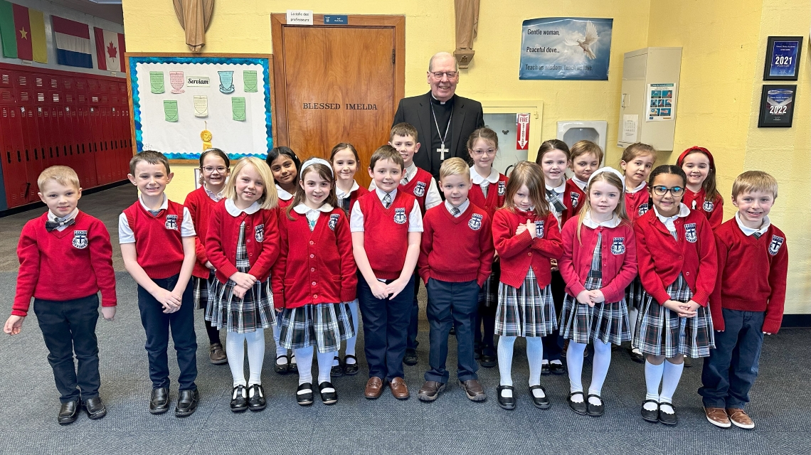Bishop surrounded by students in red sweaters