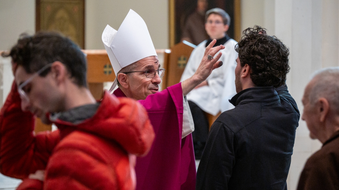 Bishop Ruggieri applies ashes to a young man's forehead