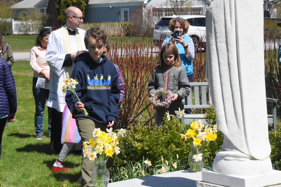 Placing flowers in vases at the foot of a statue of Mary