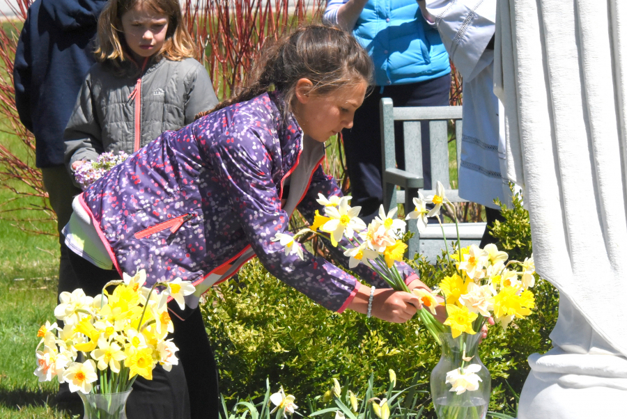 Placing flowers in vases at the foot of a statue of Mary