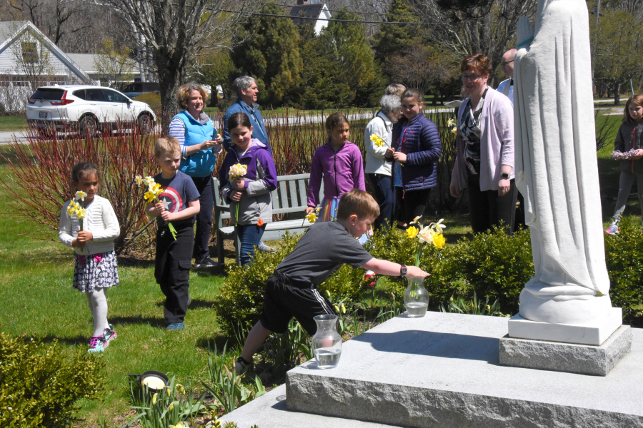 Placing flowers in vases at the foot of a statue of Mary