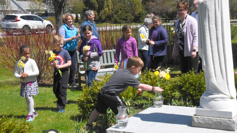 Placing flowers in vases at the foot of a statue of Mary