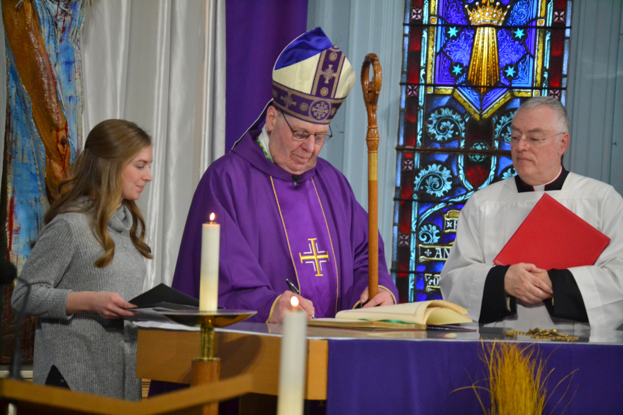 Bishop Deeley signs a Book of the Elect