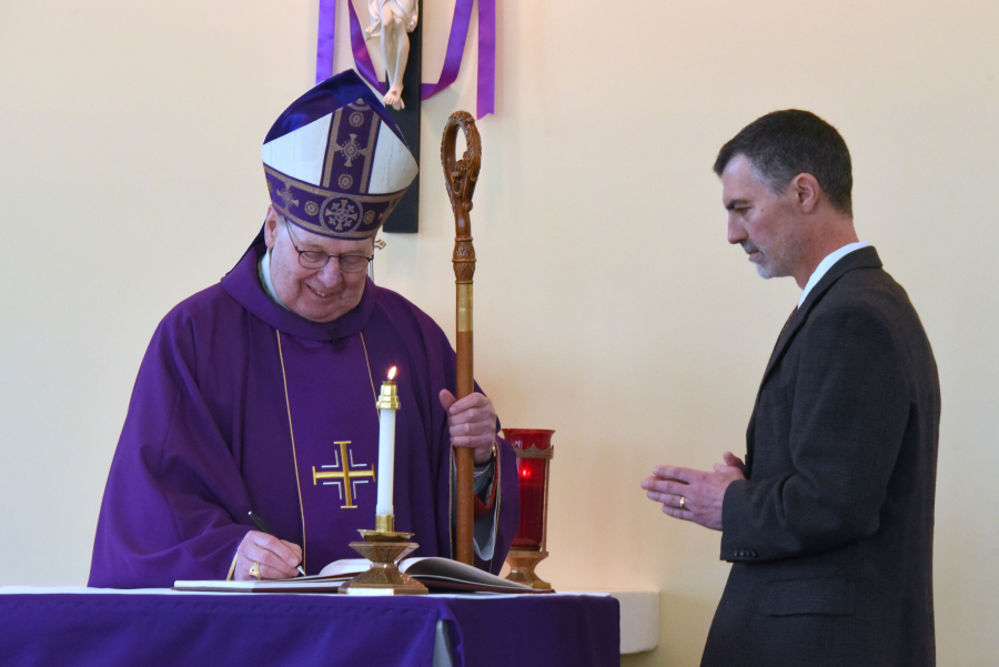 Bishop Deeley signs a Book of the Elect