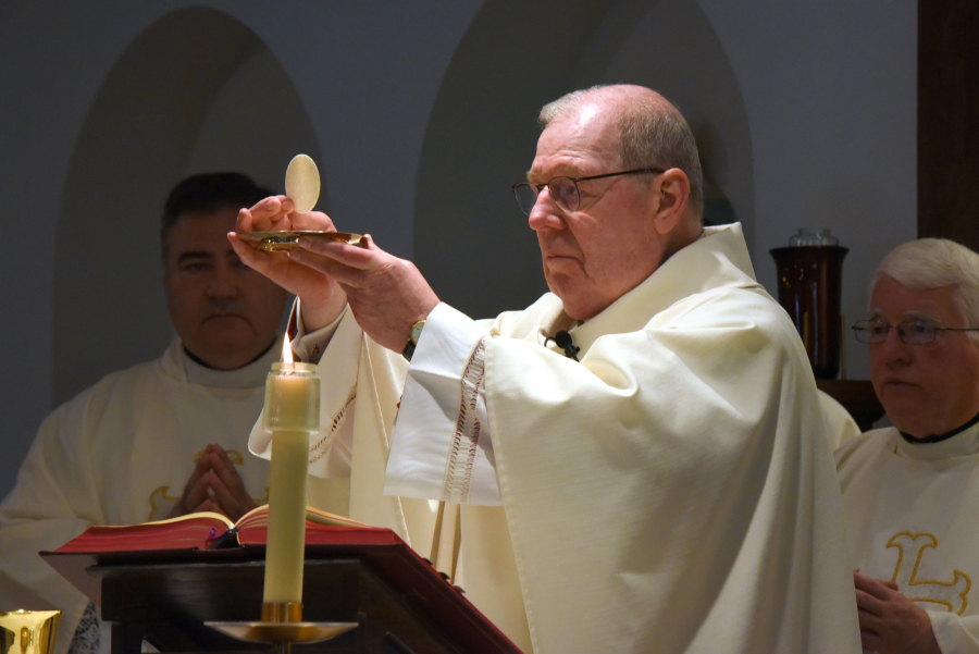 Bishop Deeley holds up the host.