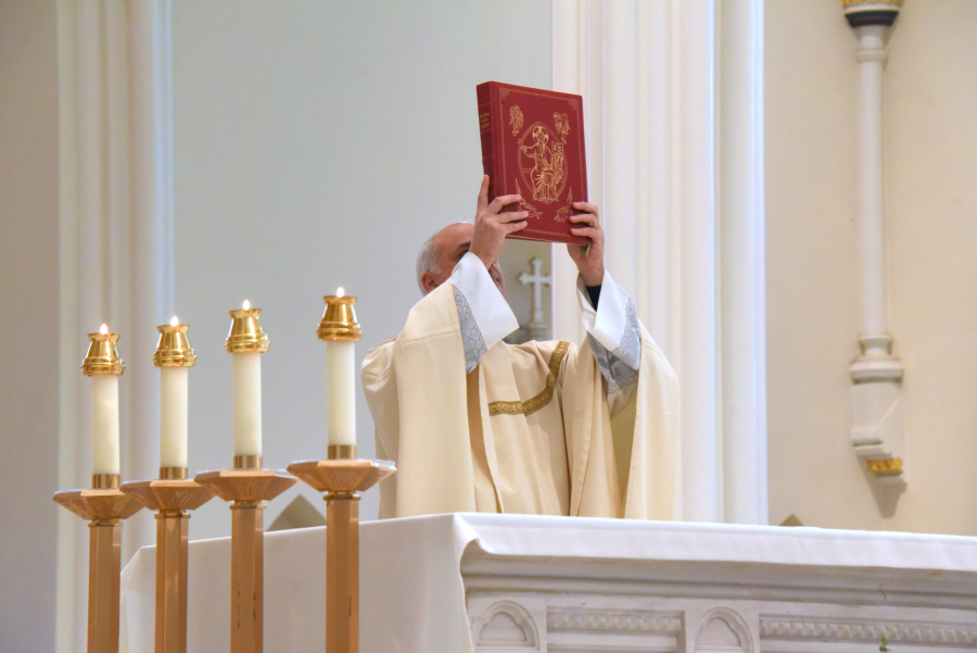 Father Seamus Griesbach holds up the Book of the Gospels