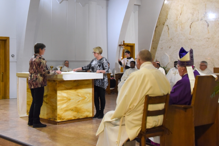 Two women dress the altar with a cloth.