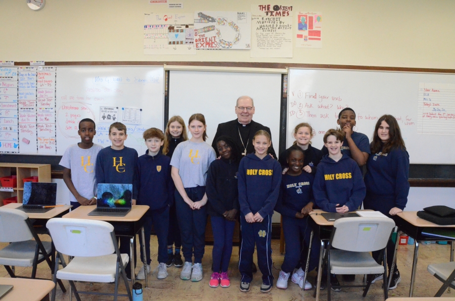 Twelve students pose standing with the bishop