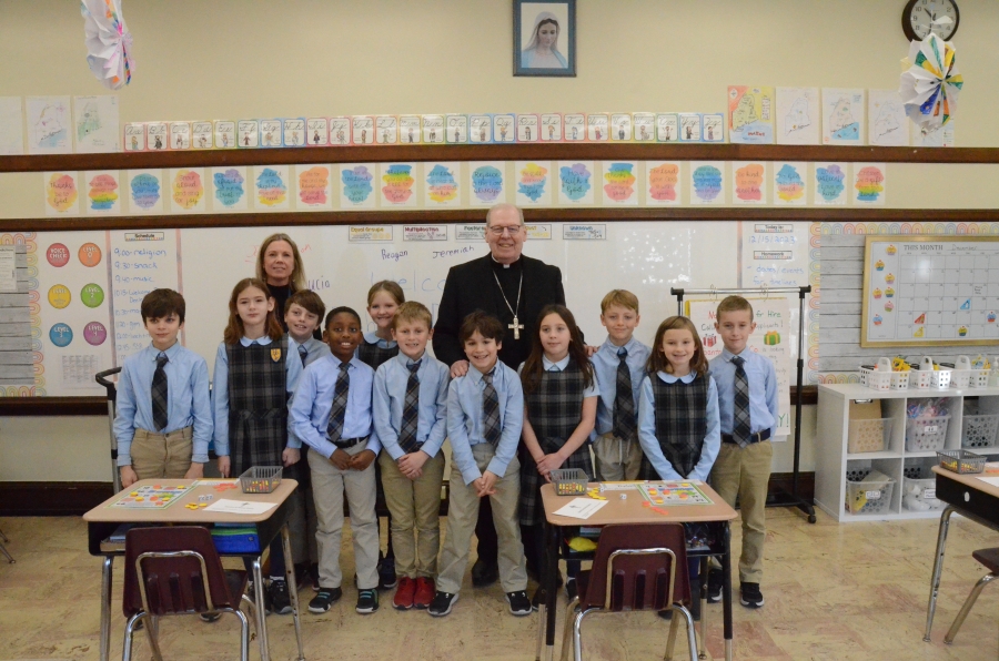 Eleven students and teacher pose with the bishop 