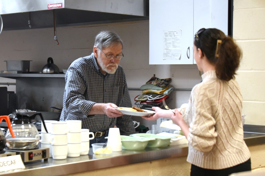 Man holding a server a plate of pancakes.