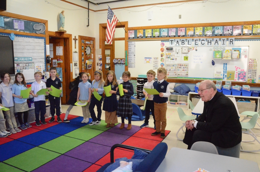 The bishop sits in front of a group of students.