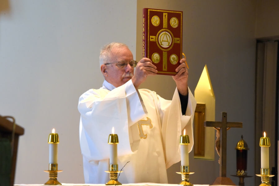 Deacon Frank Daggett holds up the Book of the Gospels.