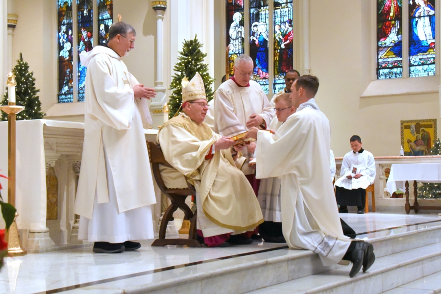 Bishop Deeley presents Deacon Valles with the Book of the Gospels.