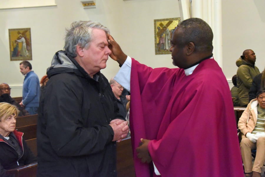 Father Augustine Kifon marks the forehead of a man with ashes.