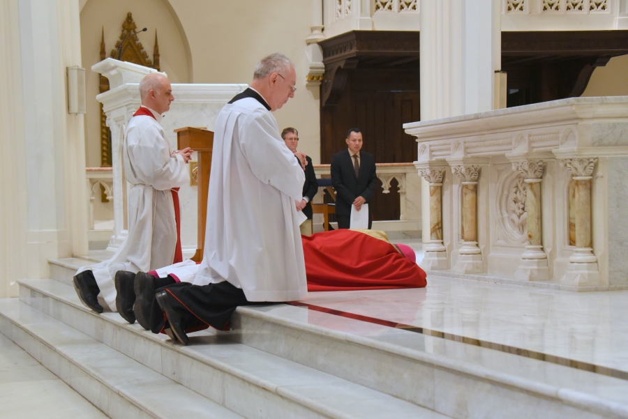 Bishop Deeley prostrates before the cro