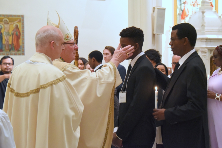 A young man is confirmed by the bishop.