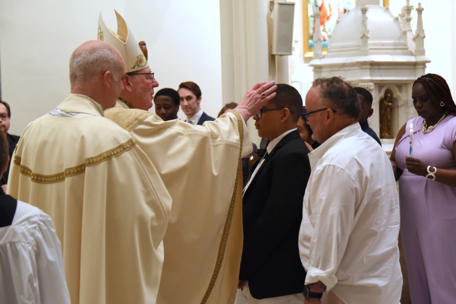 A young man is confirmed by the bishop.