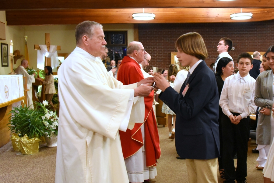 Deacon Dennis Popadak presents to the chalice during holy Communion to one of the newly confirmed.