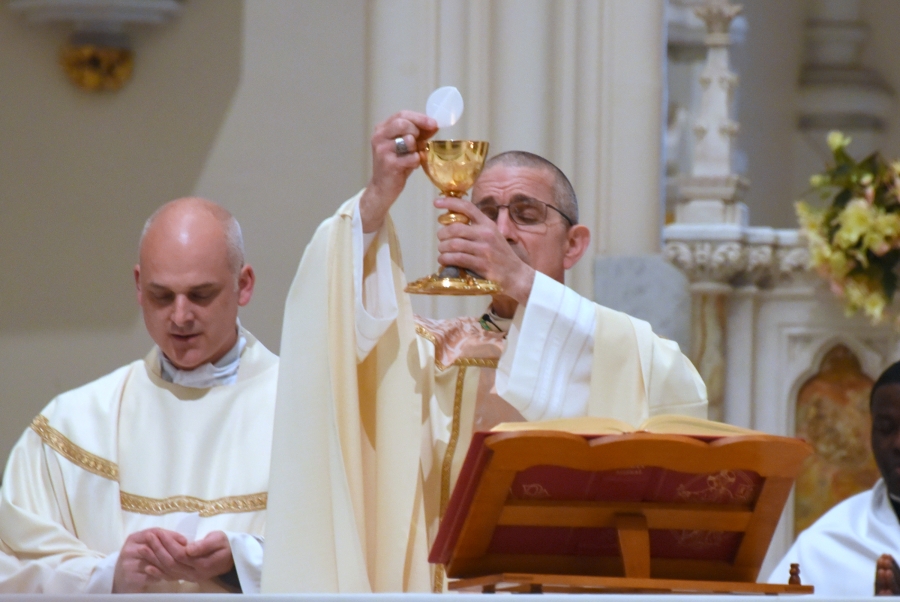 Bishop James Ruggieri holds up the host.