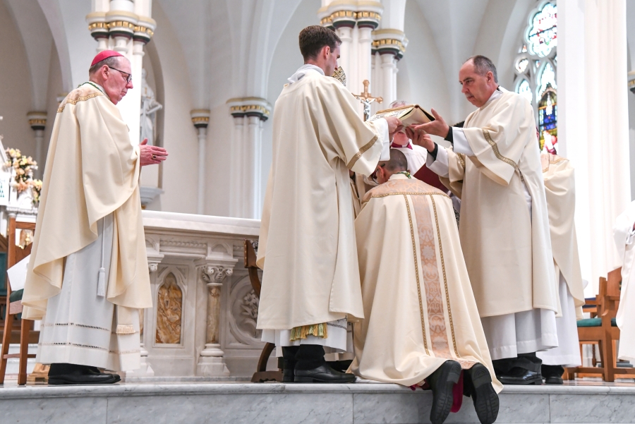Deacons hold the Book of the Gospels over Bishop Ruggieri's head while Cardinal O'Malley prays the Prayer of Ordination.