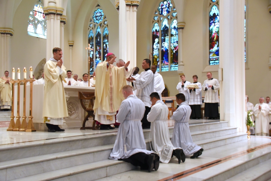 Bishop James Ruggieri prays the Prayer of Ordination for Erin Donlon, Thanh Duc Pham, and Hoa Tien Nguyen