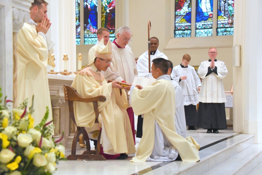 Deacon Hoa Tien Nguyen is presented with the Book of the Gospels by Bishop James Ruggieri.