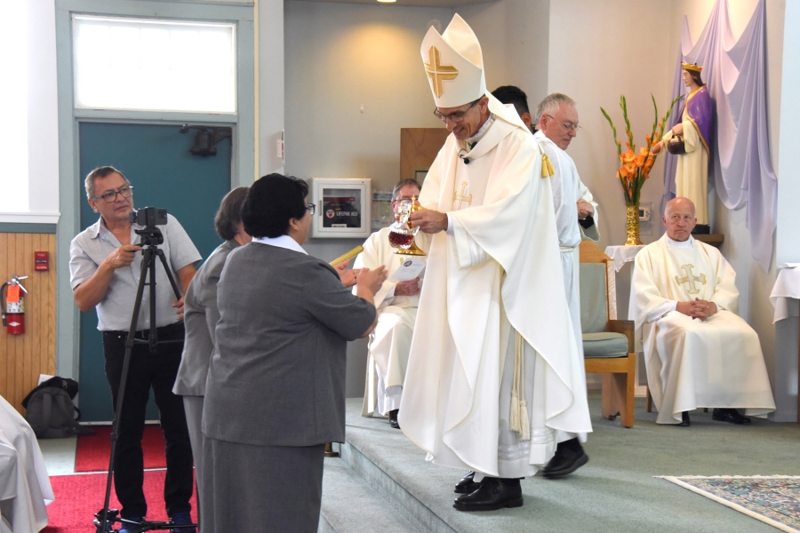 Sisters present the bishop with a plant.