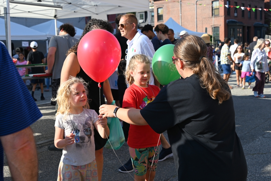 Stella hands balloons to two little girls.