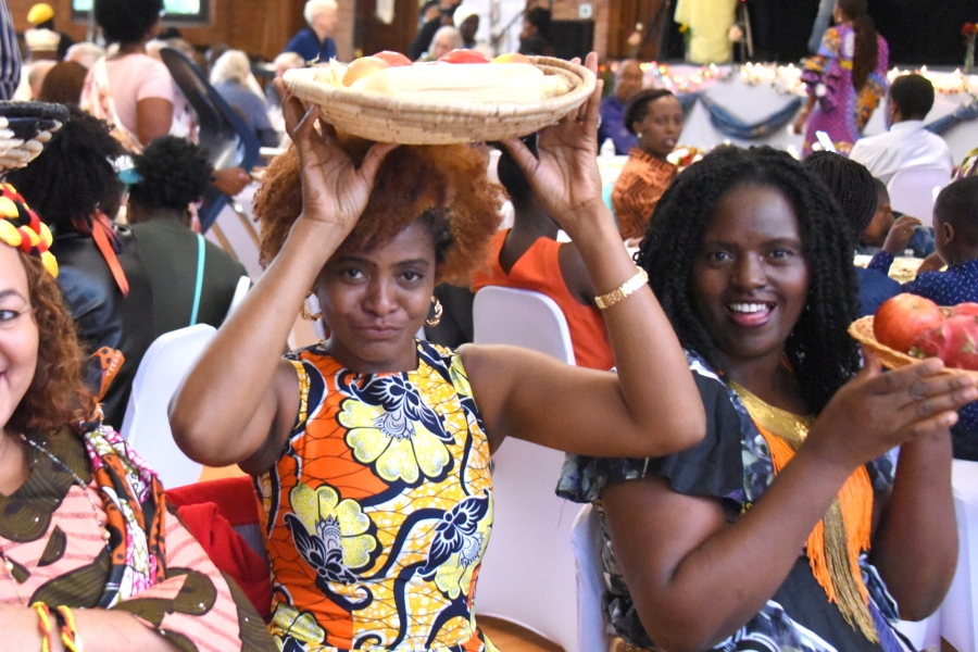 Woman with bowl of fruit on her head.