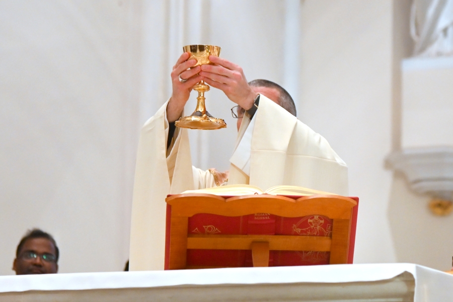 Bishop James Ruggieri holds up the cup containing the blood of Christ.