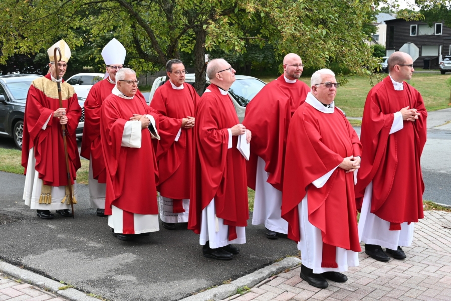 Priests and bishop outside the church wearing red vestments