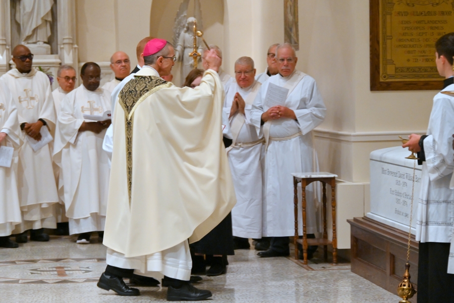 Bishop James Ruggieri sprinkles the tomb with holy water.