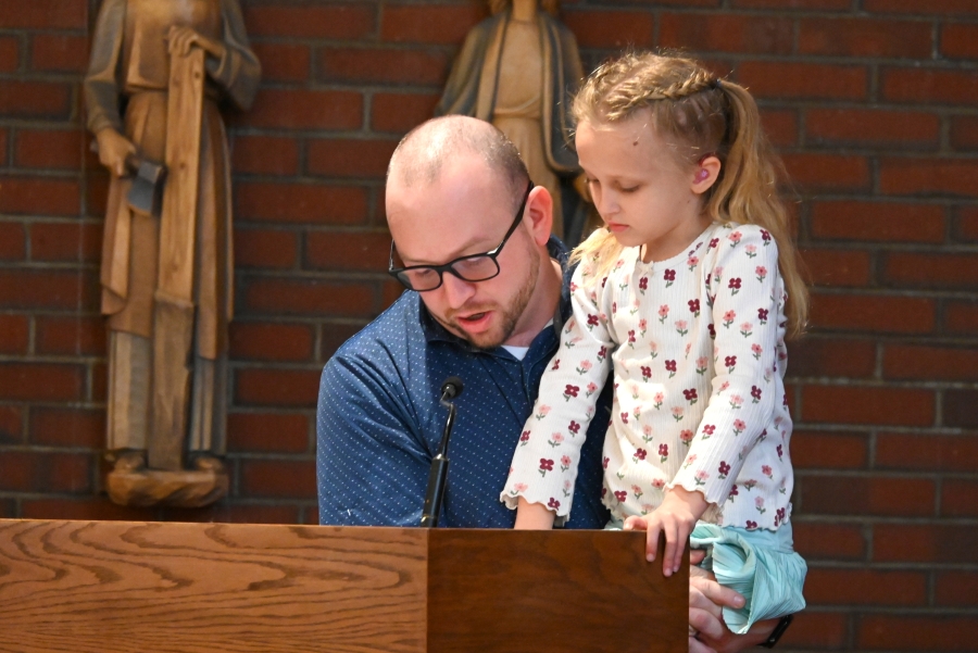 Father and daughter read one of the Stations of the Cross.