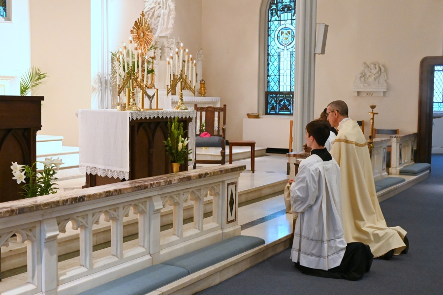 Bishop and altar servers kneel before the altar with the monstrance on it.