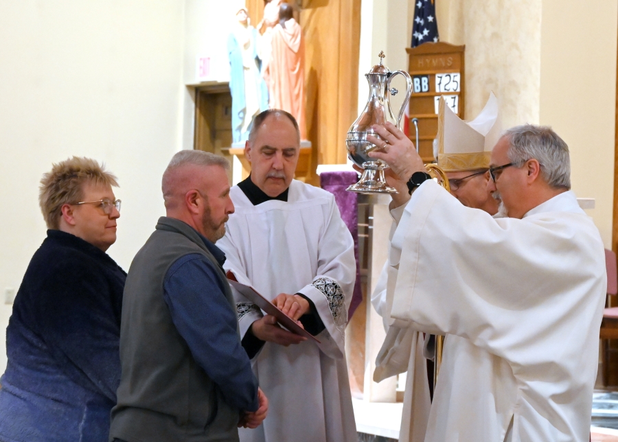 Deacon Rodney Deschaine holds up the Oil of the Catechumens.