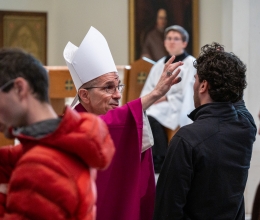 Bishop Ruggieri applies ashes to a young man's forehead