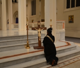 Woman kneels in from of the cross