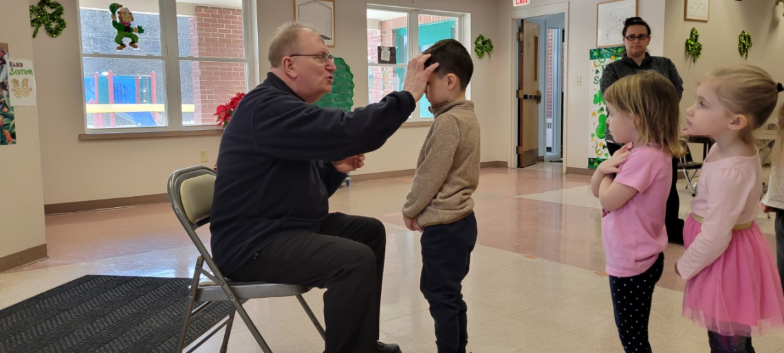 Monsignor Dubois distributes ashes to children at All Saints Catholic School in Bangor. 