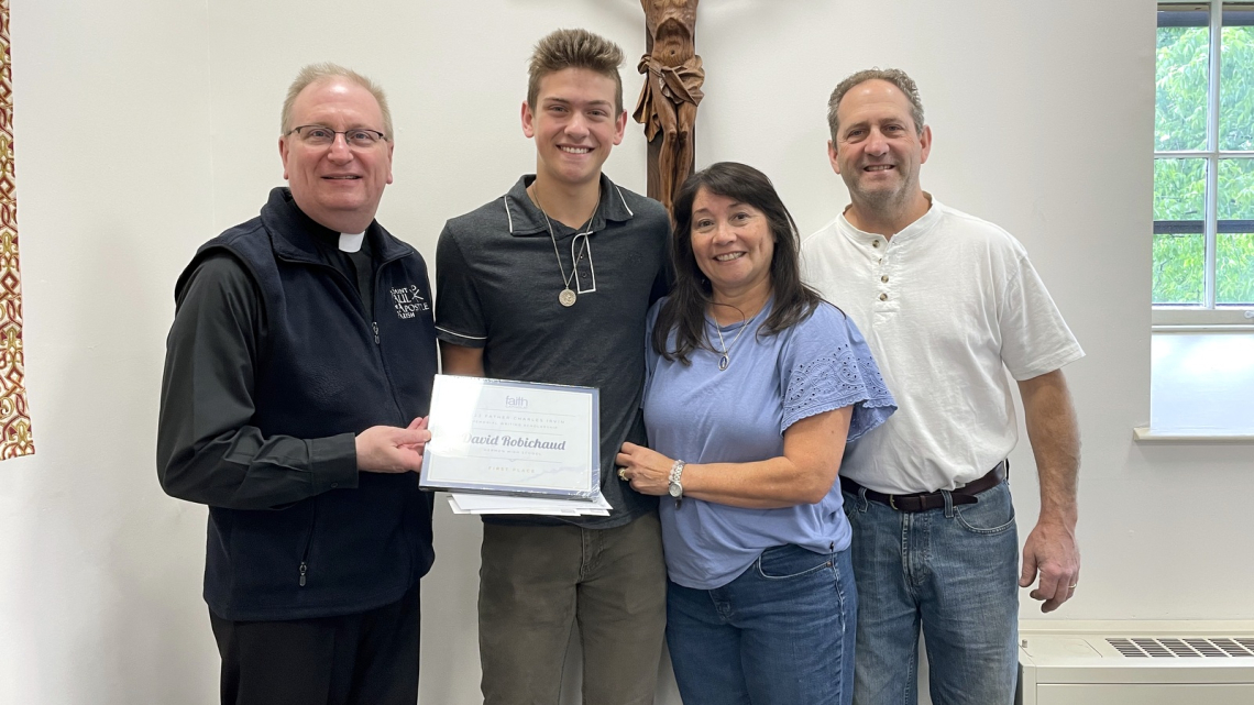 Msgr. Andrew Dubois presents a check to David Robichaud and his family.