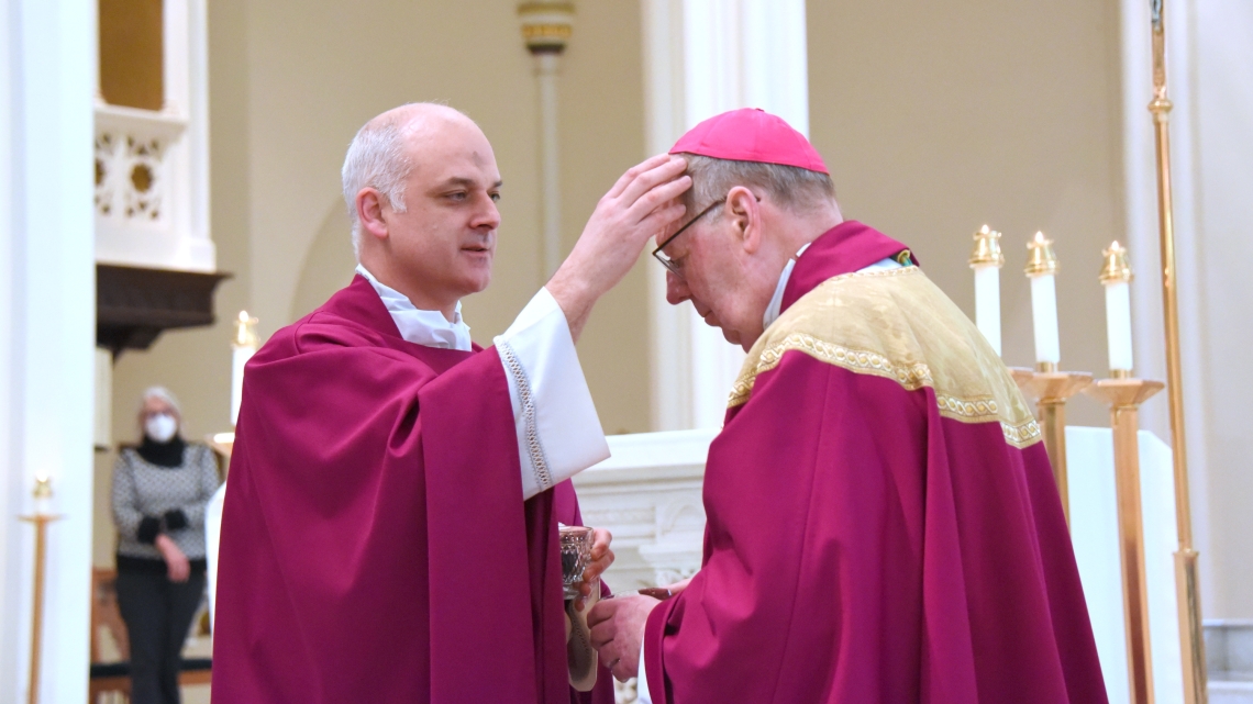 Father Seamus Griesbach marks the forehead of Bishop Robert Deeley with ashes.