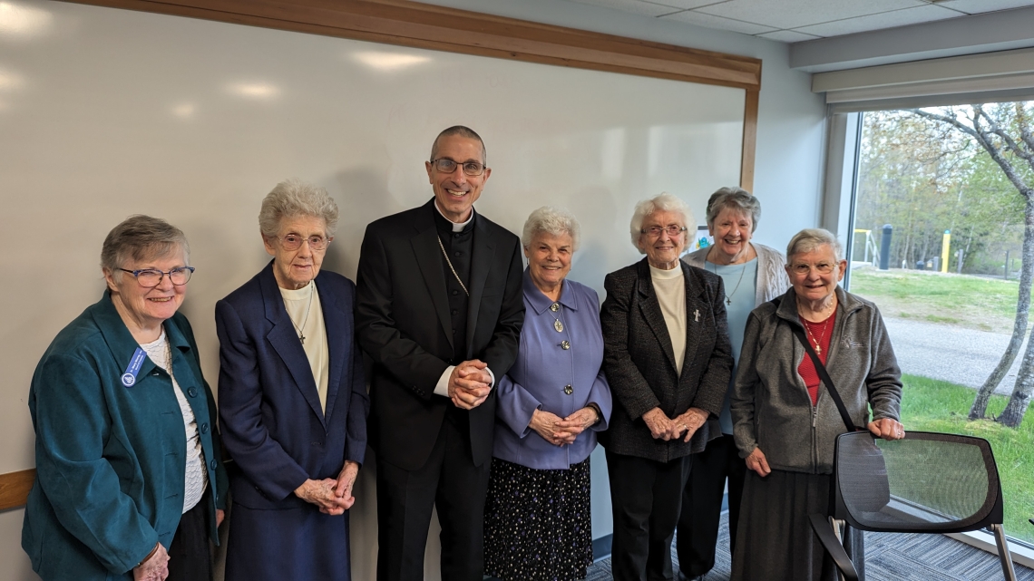 Bishop standing with six nuns