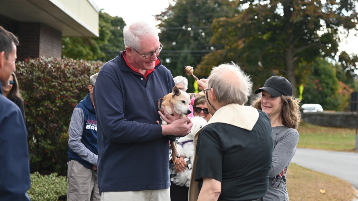 Father Michalowski sprinkles a dog with holy water.