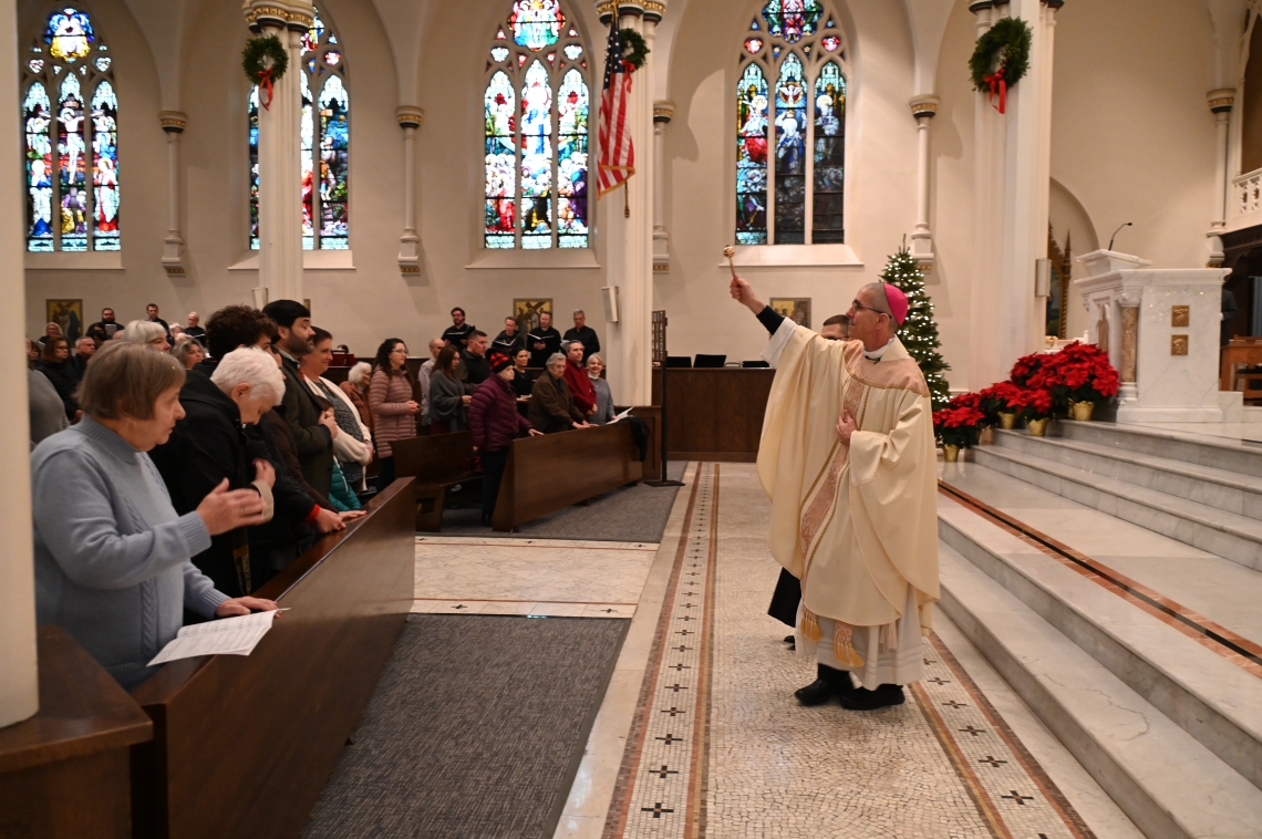 bishop sprinkles holy water at mass