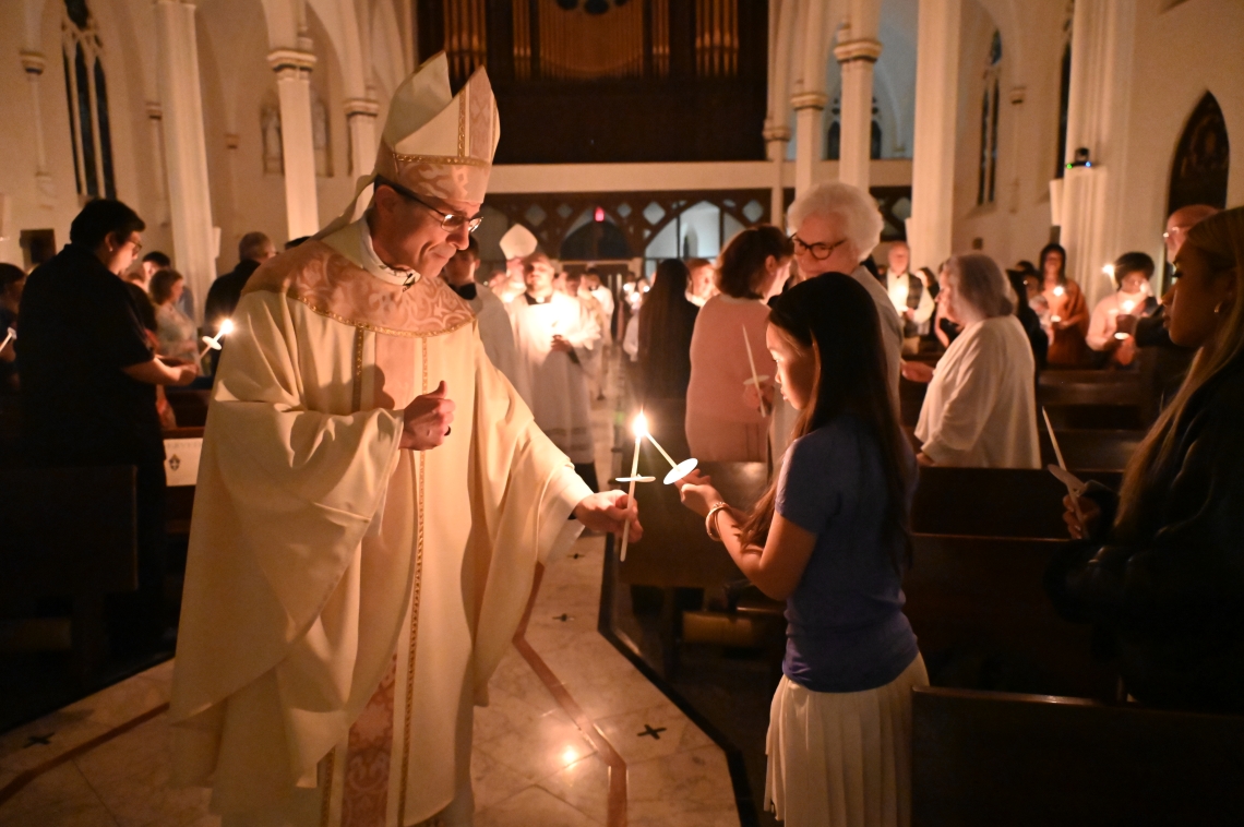 Bishop lights the candle for a young woman.