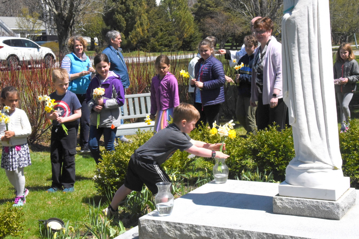 Placing flowers at the foot of the statue of Mary