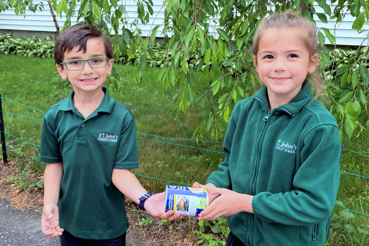 Two students hand off a can of food.